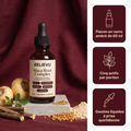 Flacon en verre ambré de 60 ml Relievu Maca Root Complex avec bouchon compte-gouttes noir, posé sur une dalle de pierre entouré de racines de maca, de graines de fenugrec et de poudre : gouttes liquides, cinq actifs par portion, prise quotidienne.