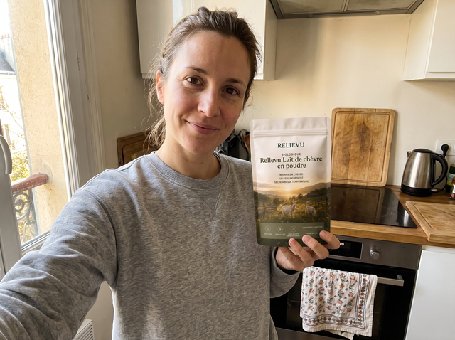 Cliente tenant le sachet de lait de chèvre en poudre dans sa cuisine