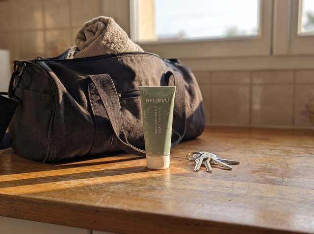 Le tube Relievu sur un plan de travail en bois, devant un sac de sport et un trousseau de clés