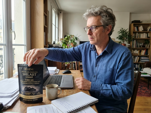 Homme à son bureau à domicile, le sachet de gommes posé à côté de son ordinateur